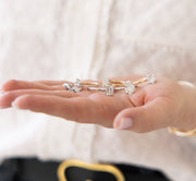 diamond engagement rings in the palm of a woman's hand