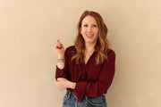 Woman wearing a burgundy blouse against a beige background