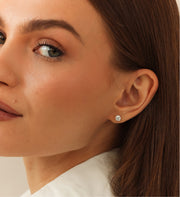 Close-up of a woman wearing a diamond earring with a neutral background