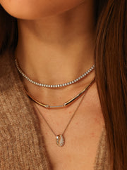 Close-up of a person wearing multiple necklaces with a neutral background