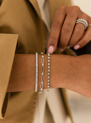 Close-up of a wrist wearing white gold tennis bracelets with a blurred background