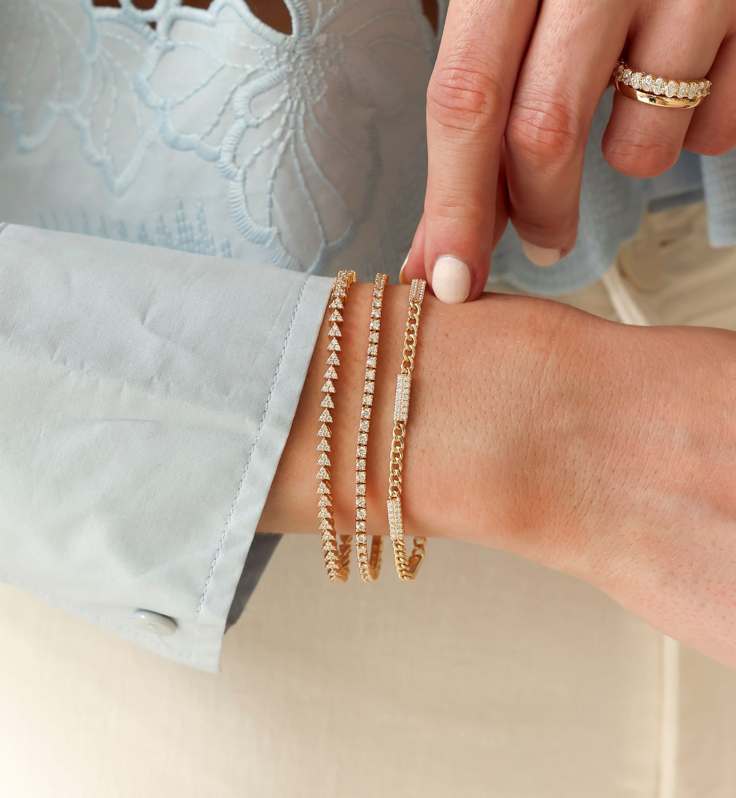 Close-up of a hand wearing gold bracelets on a light background