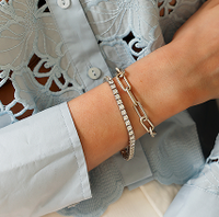 Close-up of a wrist wearing a gold bracelet with a blurred background
