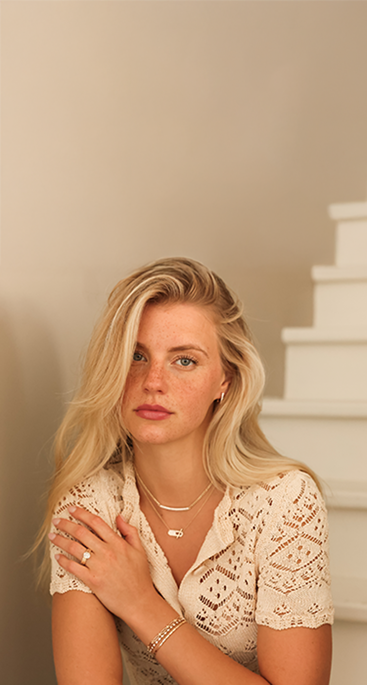 woman wearing diamond jewelry against a tan wall