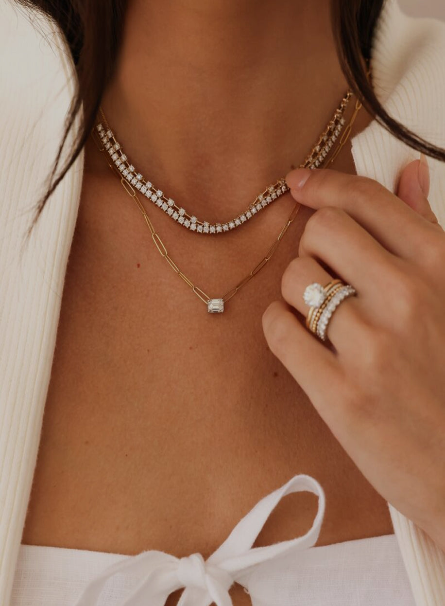 Close-up of a person wearing gold and diamond necklaces and rings.