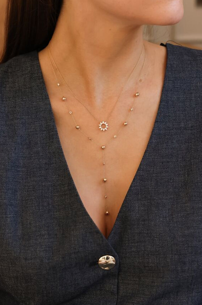 Close-up of a necklace with small gold beads and a central star-shaped pendant on a person wearing a dark blue top.
