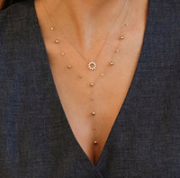 Delicate gold necklace with small beads on a dark blue garment