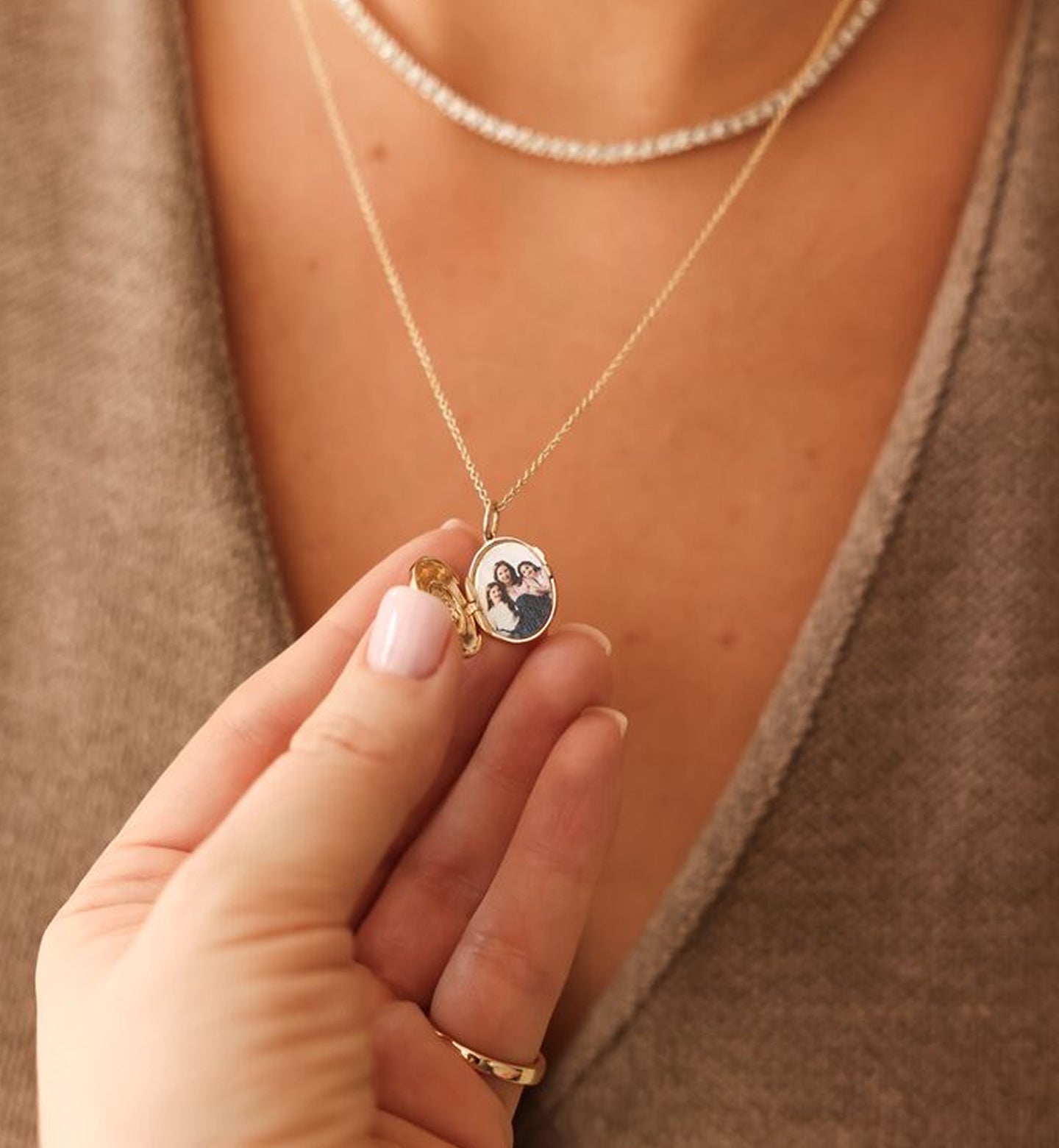 Locket with a pendant featuring a photo, held by a hand against a neutral background