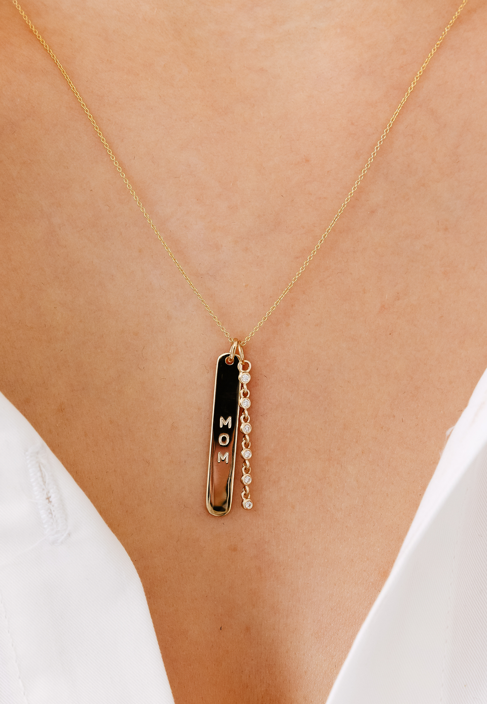 Gold necklace with an engraved pendant on a person's neck