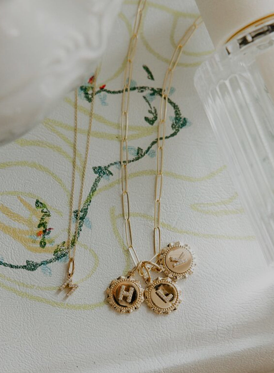 Gold necklaces with charms on a white fabric background