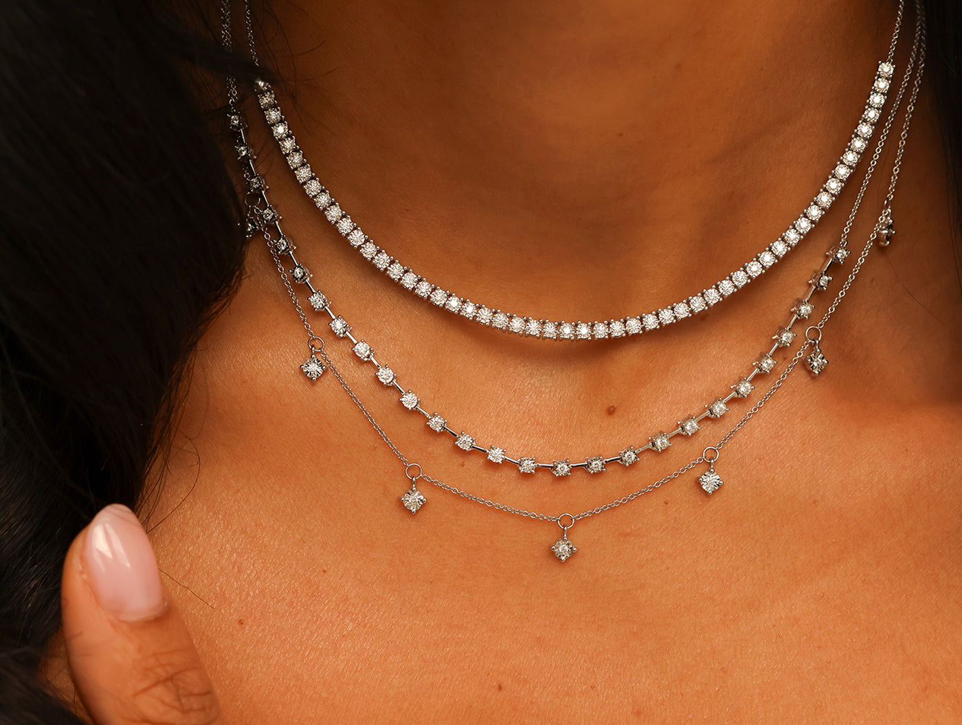 Close-up of a person wearing multiple diamond necklaces on a blurred background