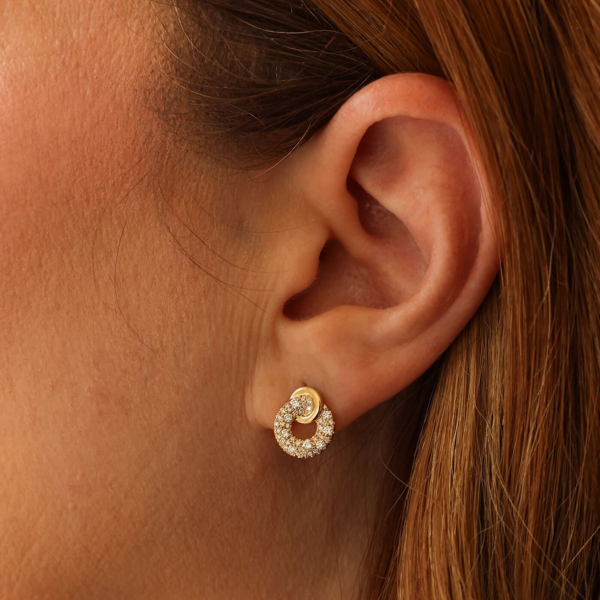 Close-up of an ear wearing a gold and diamond earring.